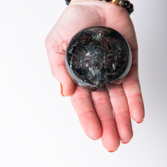 Hand holding a dark crystal ball against a white background