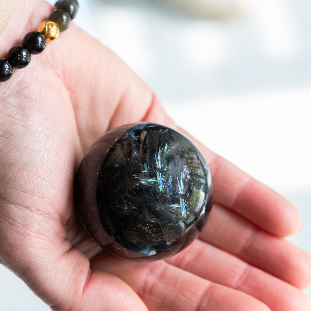 Hand holding a dark crystal ball with a blurred background