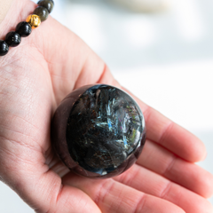 Hand holding a dark crystal ball with a blurred background