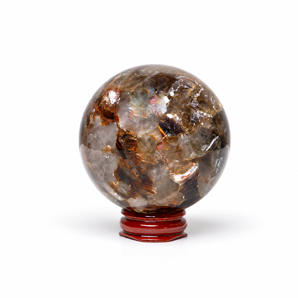 A polished round crystal sphere with natural brown, gray, and translucent patterns, displayed on a small dark red wooden stand against a white background.
