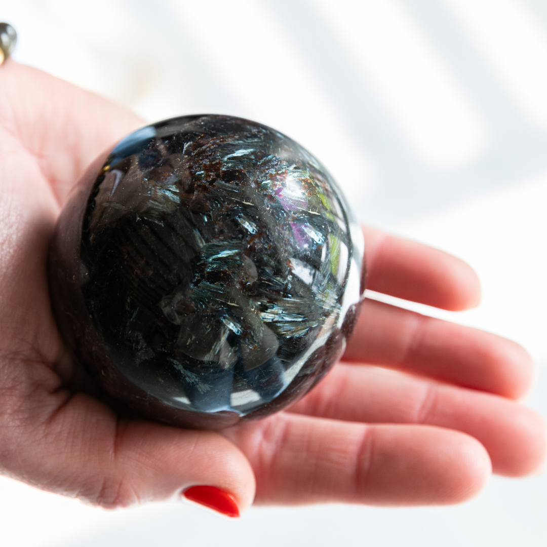Hand holding a large crystal ball with a blurred background